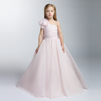Young girl in a pale pink one-shoulder gown with a large floral accent and a full floor-length skirt.