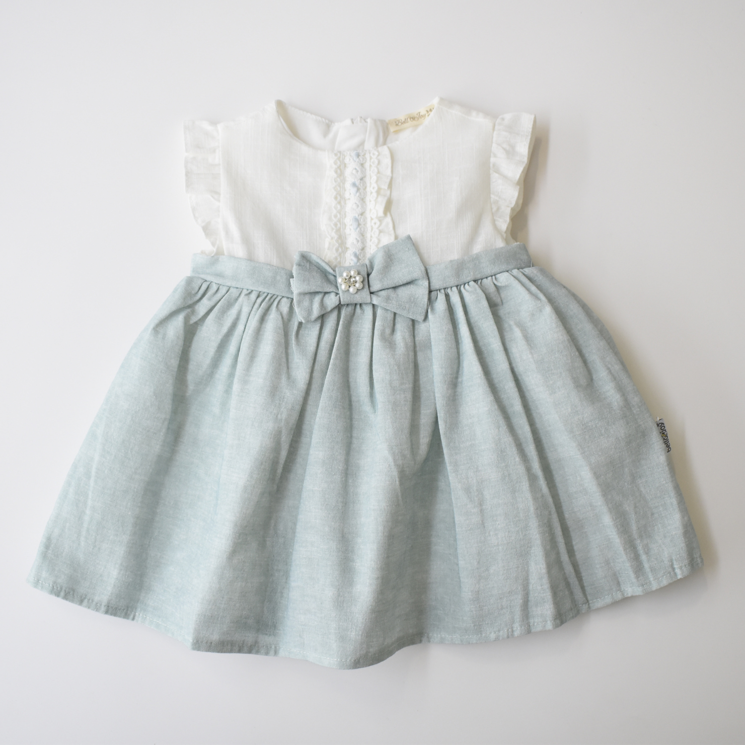 Baby girl dress with white ruffle-sleeve bodice, lace front detail, and light blue skirt accented by a bow with pearl embellishment at the waist.