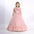 Girl in a floor-length pink tulle ball gown with one-shoulder ruffle detail and floral waist accent, styled for parties or formal occasions.