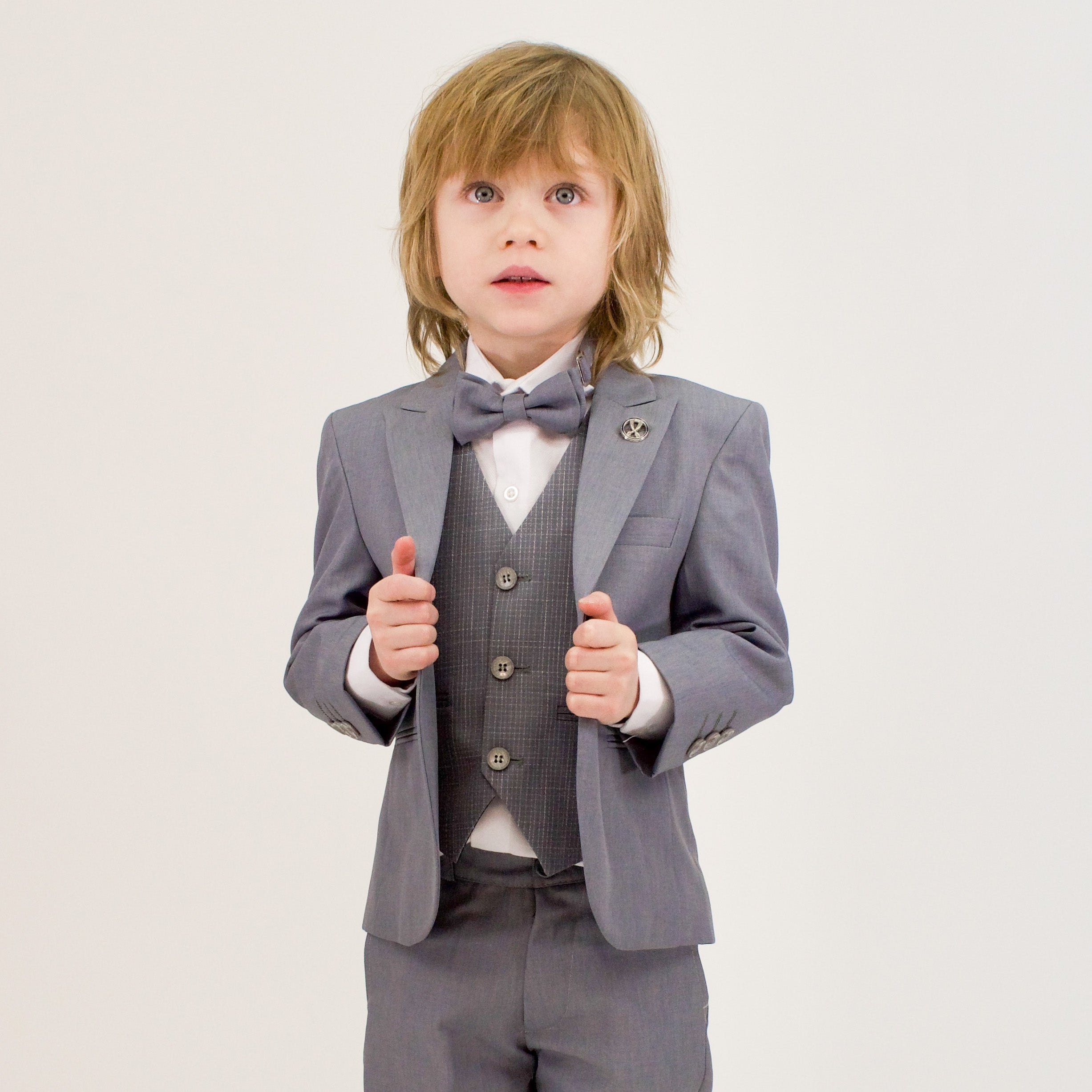 Young boy wearing a grey boys' formal suit with vest and bow tie, showcasing a tailored look ideal for formal events.