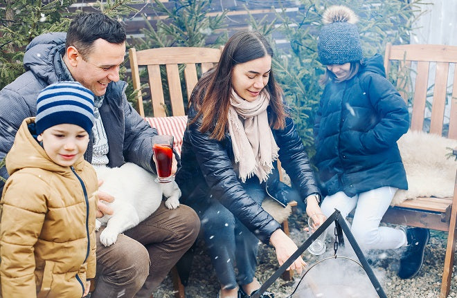 A family enjoying a fun winter activity around a campfire in Quebec.