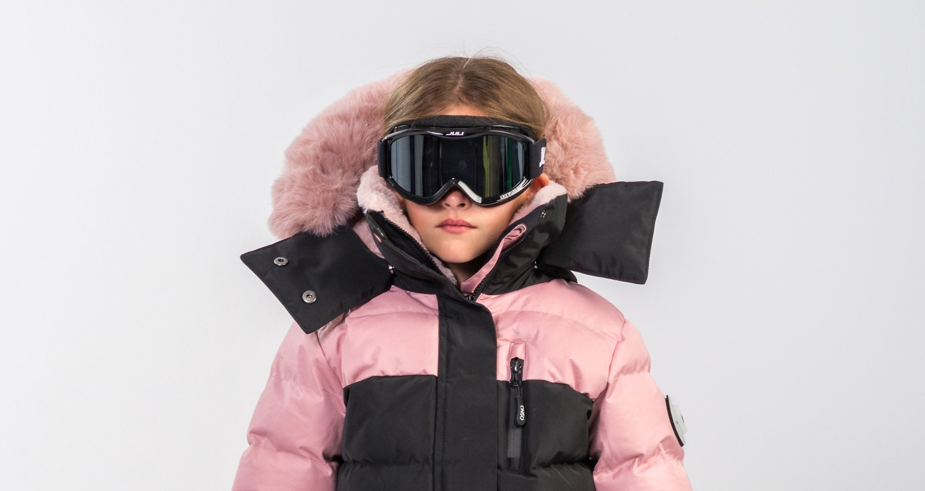 Girl wearing a black and pink OSNO kids’ snowsuit showing proper snowsuit fit at JuniorKids Canada