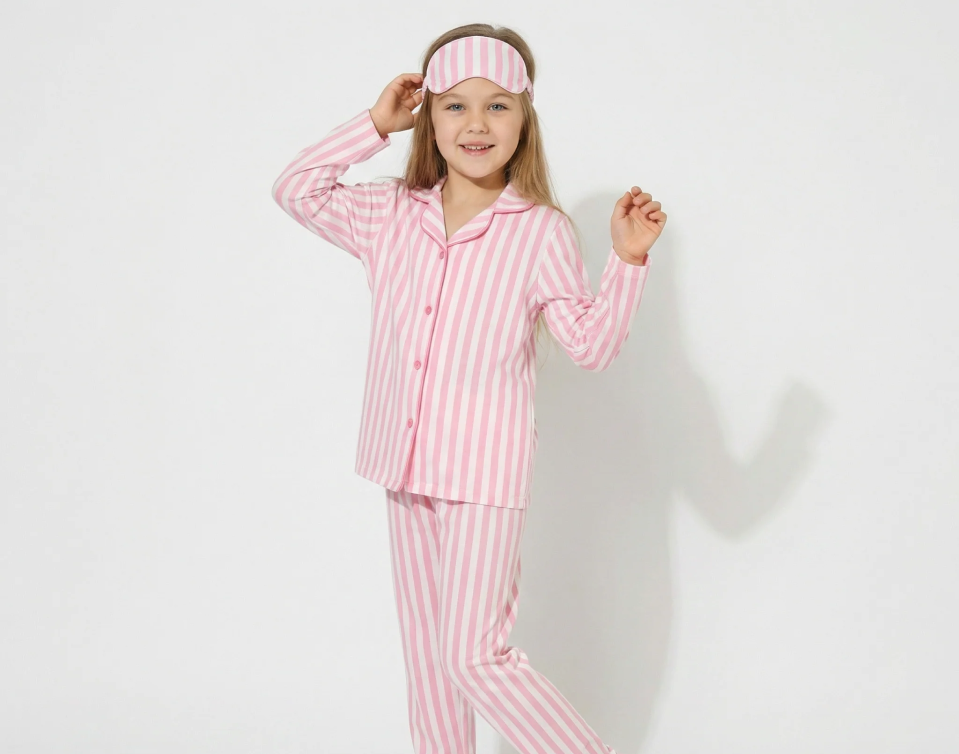 A girl in pink and white striped pyjamas with a matching headband. 